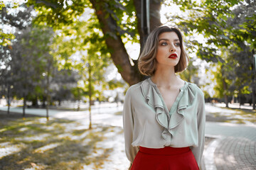 woman in red skirt walks in the park trees lifestyle