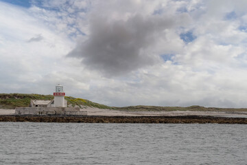 Fototapeta na wymiar Old lighthouse on Straw island, near Inishmore, Aran islands, county Galway, Ireland. Dusk time, calm cloudy sky