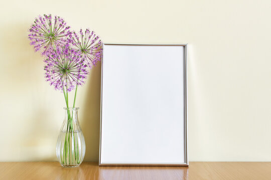 Mockup Template With A4 Frame Standing On Wooden Shelf With Three Purple Summer Flowers Branches In Glass Vase.