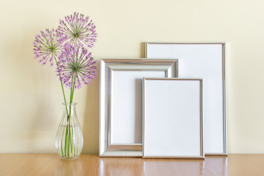 Mockup template with three silver frames and purple flowers in glass vase.