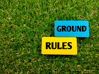 Colorful wooden board with text GROUND RULES on grass background.