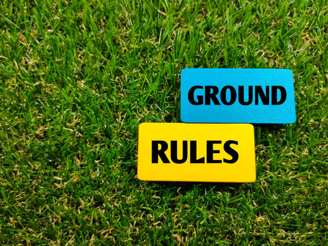 Colorful wooden board with text GROUND RULES on grass background.