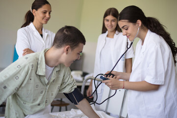 Young student in hospital measures the patient's pressure. - 441707846