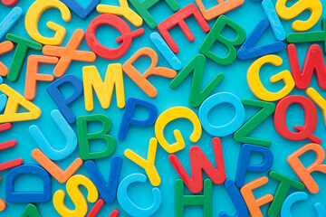 Flat lay of colorful word alphabets letter on blue background. English language education, kids development or back to school concept.