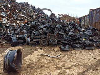 a lot of broken rims in a junkyard. A pile of broken car rims in a junkyard. Worn metal car rims...
