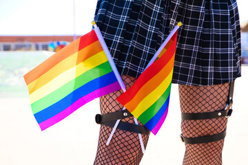 girl's leg detail with fishnet stockings and leather garters on which you can see two gay pride flags intertwined with each other. Concept gay lesbian freedom and rights.