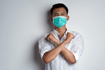 Portrait of young asian man standing and hand crossed in front of her chest posing like he ready to protect from the virus against white background. Symptoms of contracting corona virus concept 