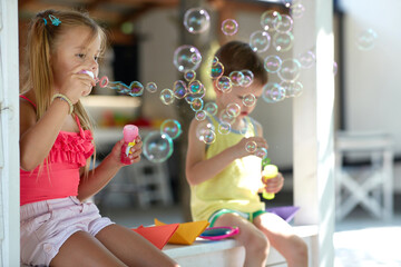 little girl teaching her brother how to make soap bubbles
