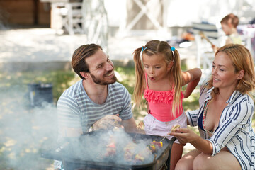 parents teaching  daughter how to make barbeque