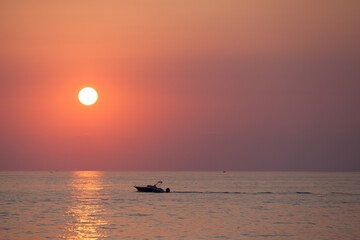 Sunset seascape with a silhouette of a motor boat sailing near Valletta