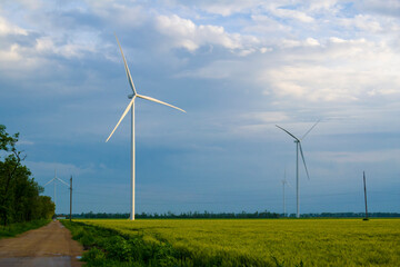 wind farm in the wheat field. in the background of the sky covered with clouds