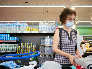 A woman wears a face mask while shopping in a supermarket