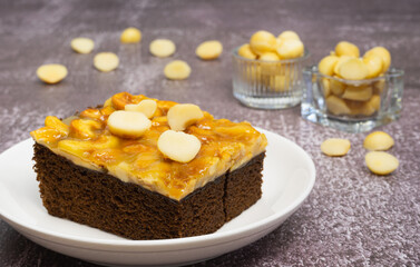 Toffee chocolate cake slice with macadamia seeds in two small bowls on stone background for dessert break