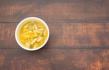 Left frame, soft tom yum soup with omelet, mushroom, galangal, lemongrass in white bowl on wood table frame, soft tom yum soup with omelet, mushroom, galangal, lemongrass in white bowl on wood table