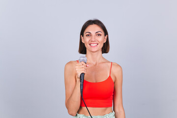 Beautiful woman on gray background with microphone look to camera with smile