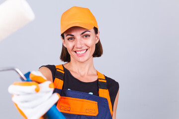 Painter woman with roller brush on gray background positive smiling happy