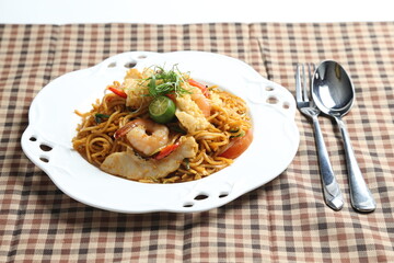 stir fried spicy chilli noodle mamak mee goreng with mixed seafood fish, prawn, squid, meat and lime asian halal menu