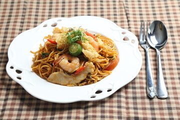 stir fried spicy chilli noodle mamak mee goreng with mixed seafood fish, prawn, squid, meat and lime asian halal menu