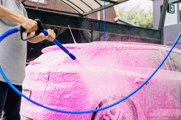 Car wash with soap, Car cleaning with high pressure water, a person washes the car, washes off the foam with water