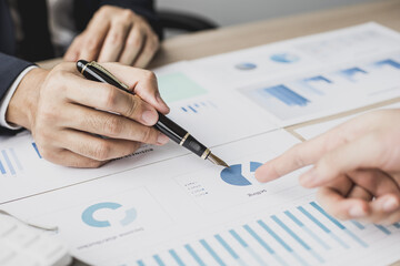 Two businessmen pointing at a chart on the document, they are startup friends together, business partners shaking hands after brainstorming and planning a startup company. Startup company concept.