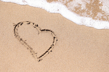 Drawn heart on wet sand next to sea closeup