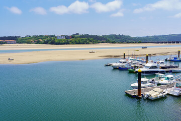 Fototapeta na wymiar White sand beach with boats anchored in the marina on sunny summer day. Santander.