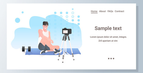male fitness trainer recording video blog using camera on tripod live streaming blogging workout concept