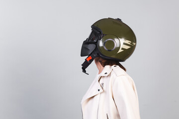 Woman in leather jacket and helmet on gray background