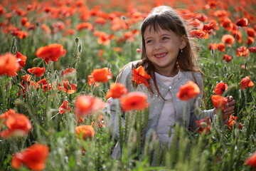 Little girl walks in a beautiful field of poppies