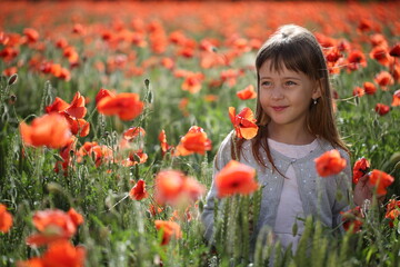 Little girl walks in a beautiful field of poppies