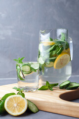 Delicious cold summer lemonade with cucumber and mint in stone jars on a light slate, stone or concrete background.