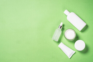 Natural Cosmetic products at green background. Cream, serum bottle and tonic. Top view image with copy space.