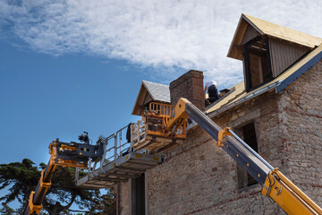 Fototapeta na wymiar A roofer renovates the roof of an old Breton stone house