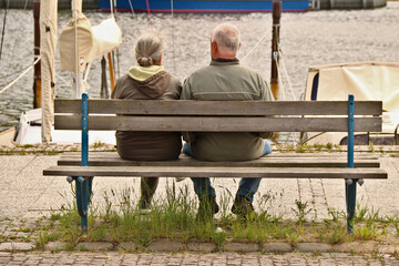 zwei Senioren Mann und Frau sitzen auf einer Bank am Hafen