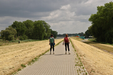 zwei junge Frauen mit Rollschuhen auf einem Radweg