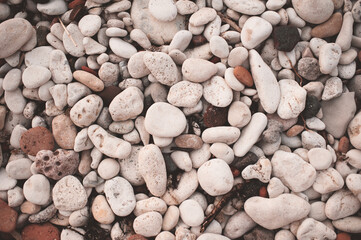 Different color beach stone pebbles at seashore outdoors top view. Nature background and textures. Summer vacation season.