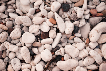 Different color beach stone pebbles at seashore outdoors top view. Nature background and textures. Summer vacation season.