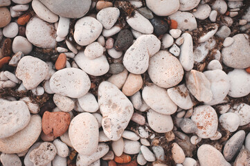Different color beach stone pebbles at seashore outdoors top view. Nature background and textures. Summer vacation season.