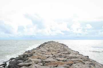 cloudy sky and a man made rocky path made with large stones on the beach