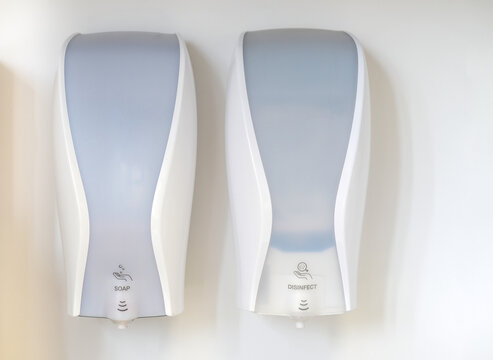 Konzept Hygiene und Sauberkeit: Zwei Spender mit Desinfektionsmittel und Seife an einer wei&szlig;en Wand 