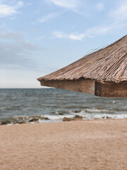 Thatched roof canopy against the backdrop of the sandy beach and blue sea. Summer rest.