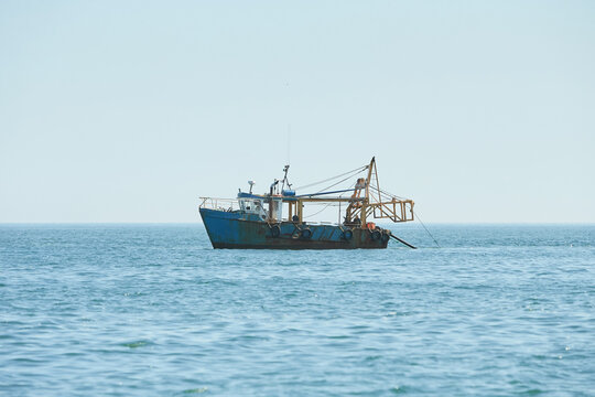 Fishing boat, trawler fishing Razor fish in an open Irish sea. Food industry, traditional craft, environmental damage concepts.
