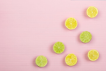 halves of lemons and limes on pink wooden background