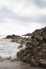 Obraz premium Vagues s'écrasant sur les rochers de la plage du Pero de Cargèse, en Corse. Photo verticale.