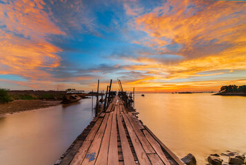 Fototapeta premium Burning the sky on the wooden pier in the fishing village of batam island