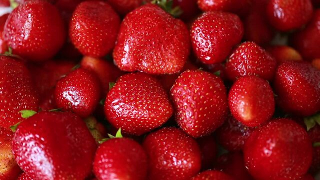 Ripe juicy strawberries slowly rotate. Summer harvest of sweet berries. Background of fresh delicious fruits