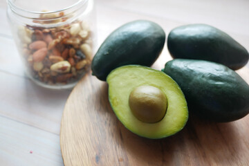 close up of slice of avocado and mixed nut on chopping board.