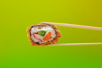 Sushi roll asiático con aguacate, salmón, cangrejo y arroz sujeto con palillos de madera 
