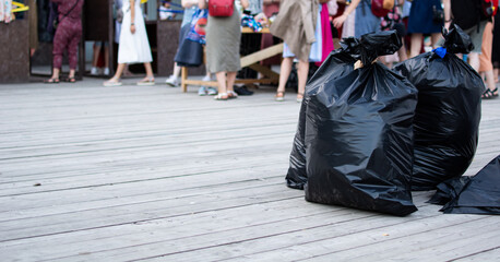 Black garbage bags on the wooden floor. Awaiting sorting or eliminated. Charity and recycling concept.