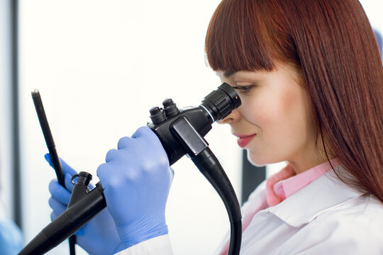 Instrument for endoscopy in the hands of pretty young Caucasian female doctor, performing gastrointestinal fiberoptic endoscopy. Close up portrait.
